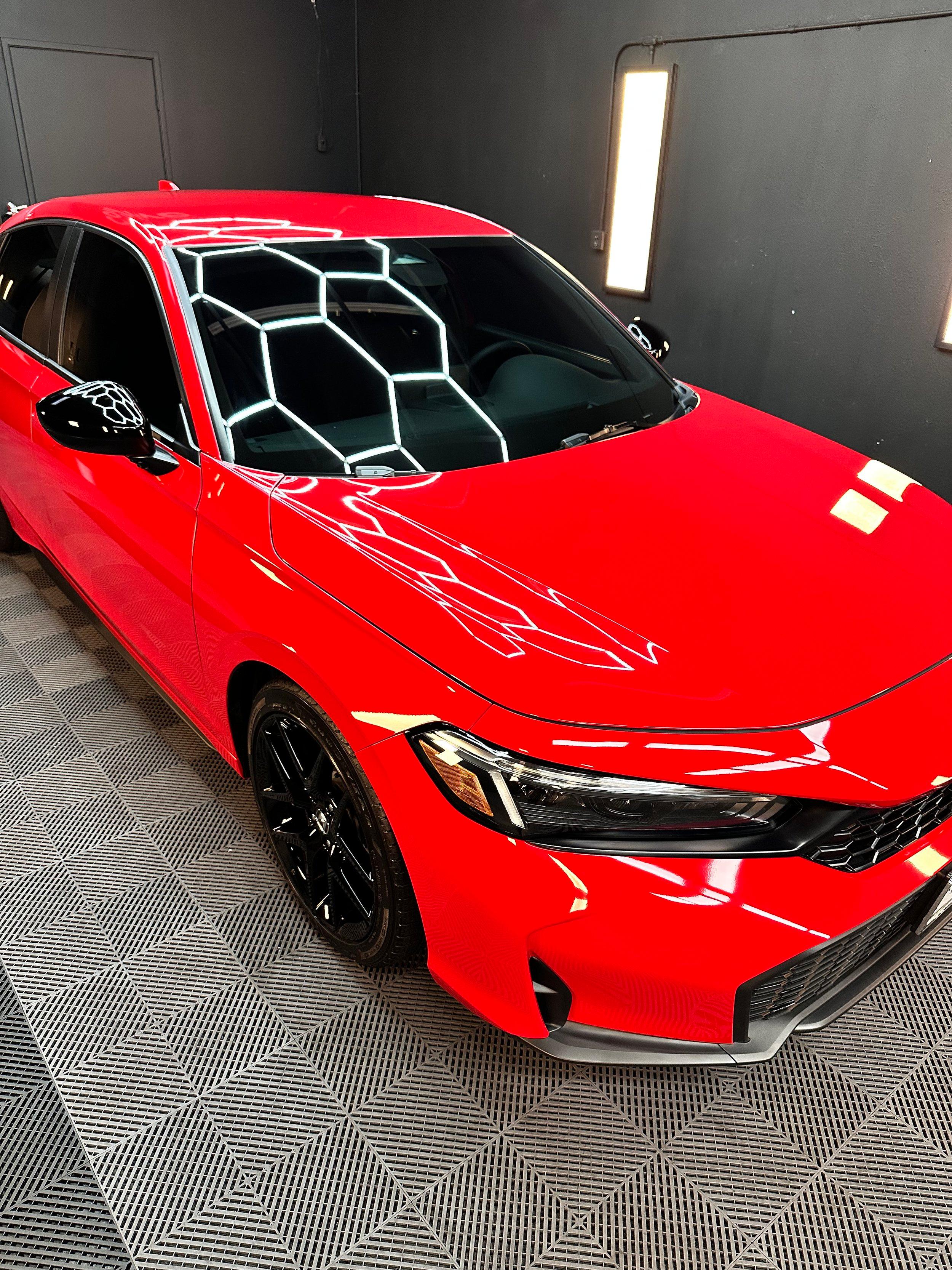 Red Honda Civic with the studio hexagon lights reflected sharply in its corrected paint