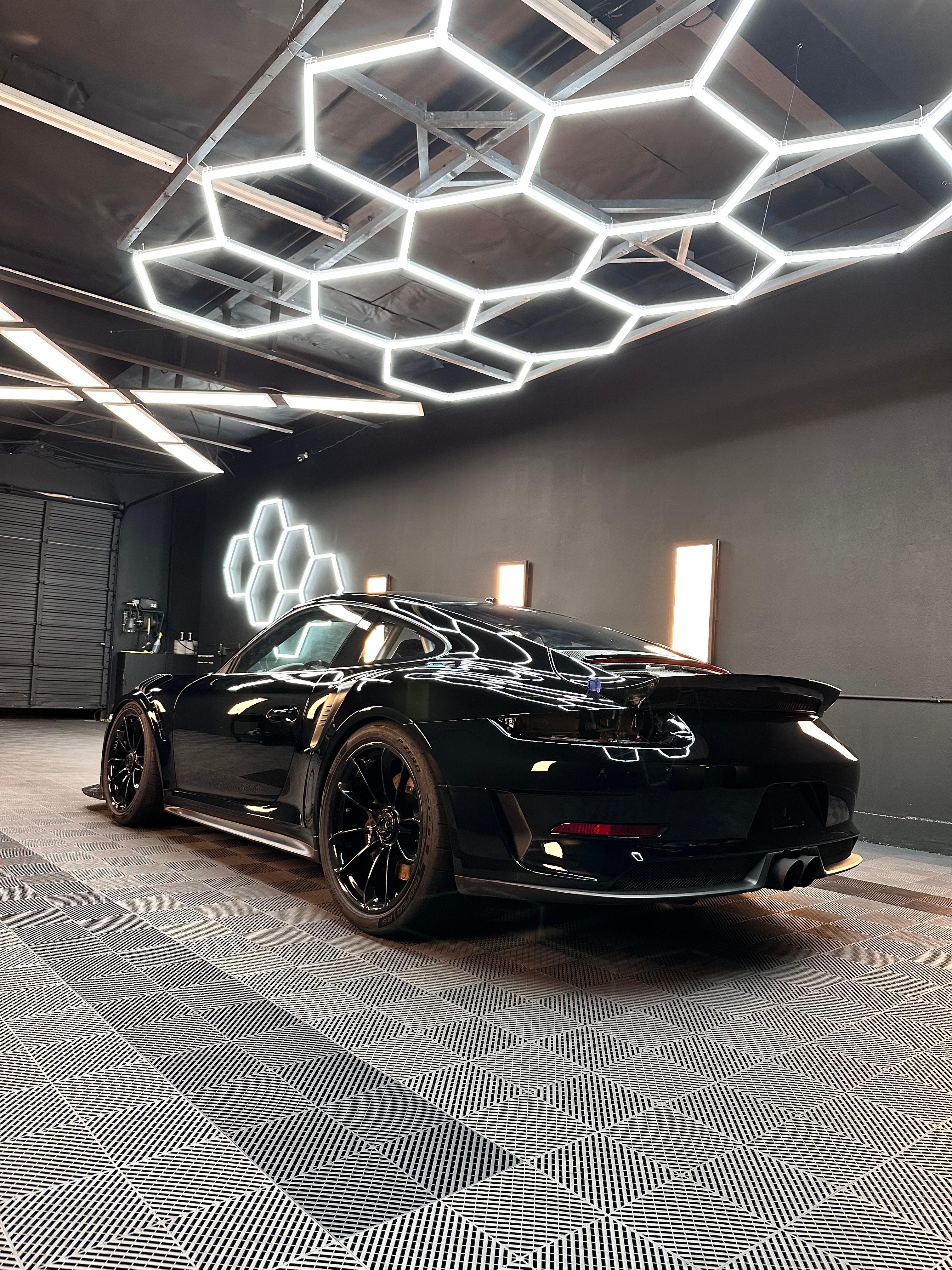 Black Porsche 911 GT3 from the rear three-quarter under the hex lights