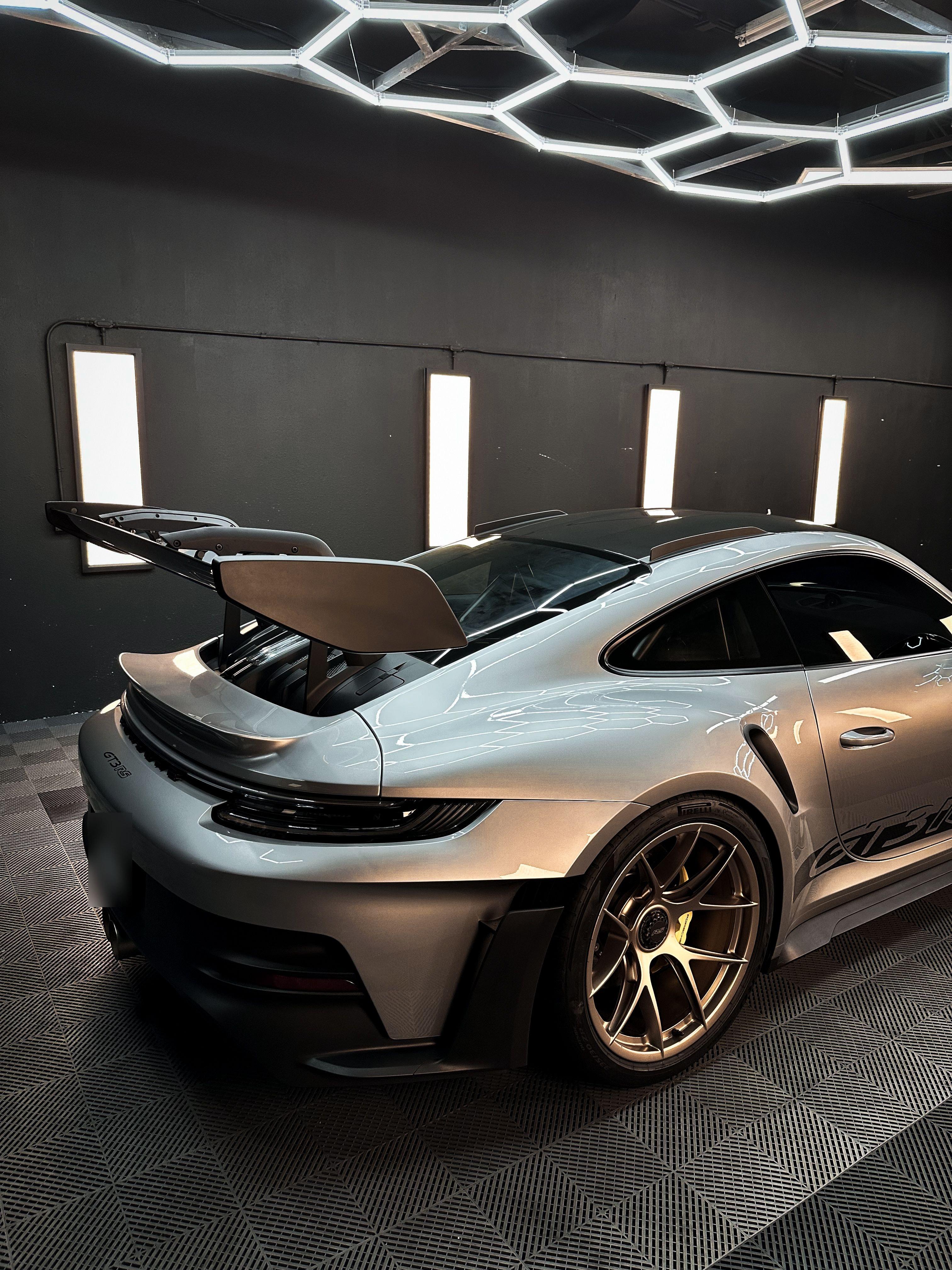 Silver Porsche 911 GT3 RS rear wing and bronze wheel in the studio