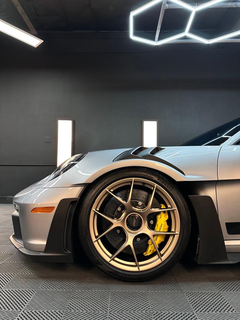 Close-up of a silver Porsche GT3 RS front wheel with yellow calipers and bronze spokes in the bay