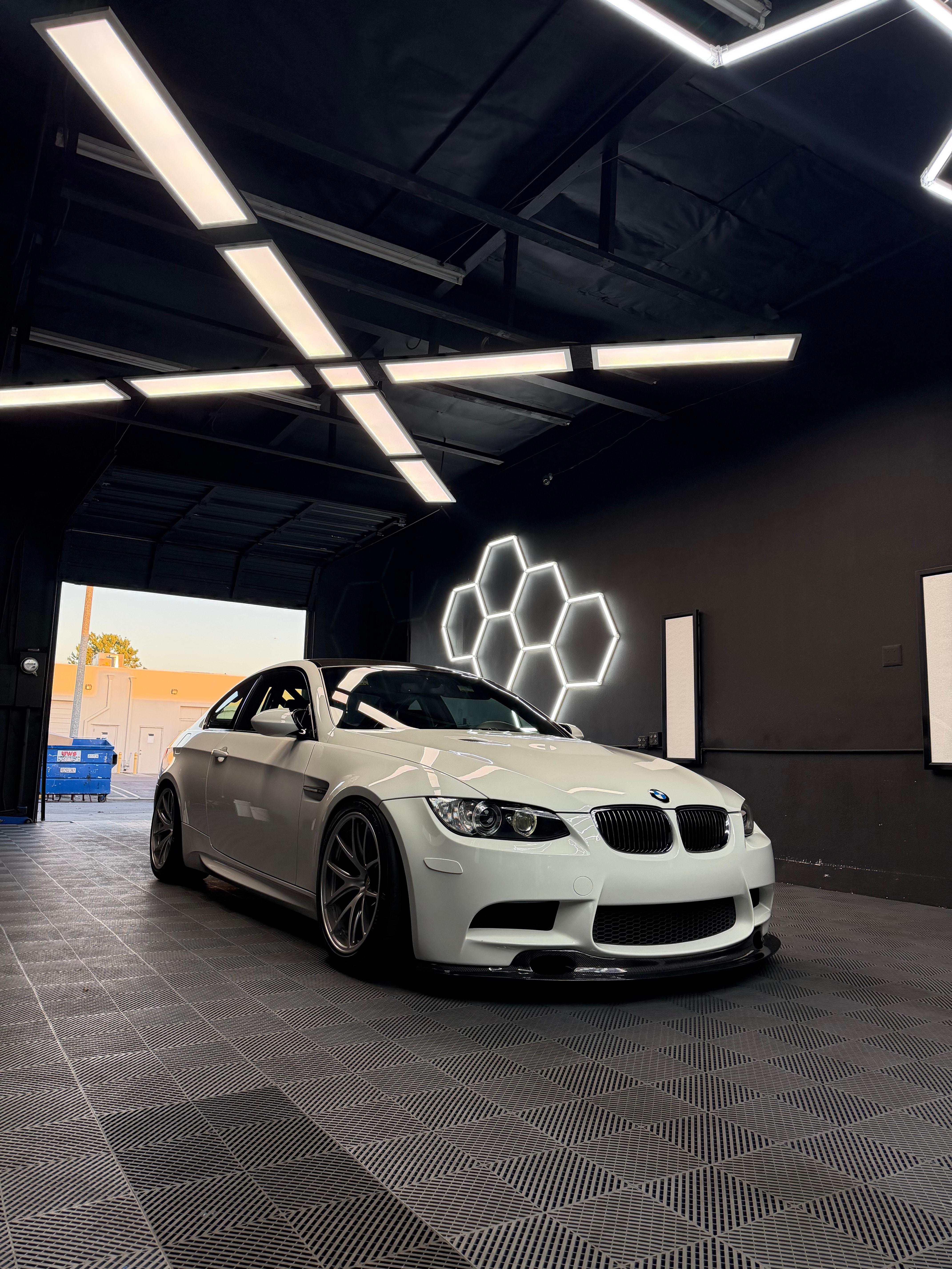 White BMW E92 M3 in the studio with the bay door open behind it
